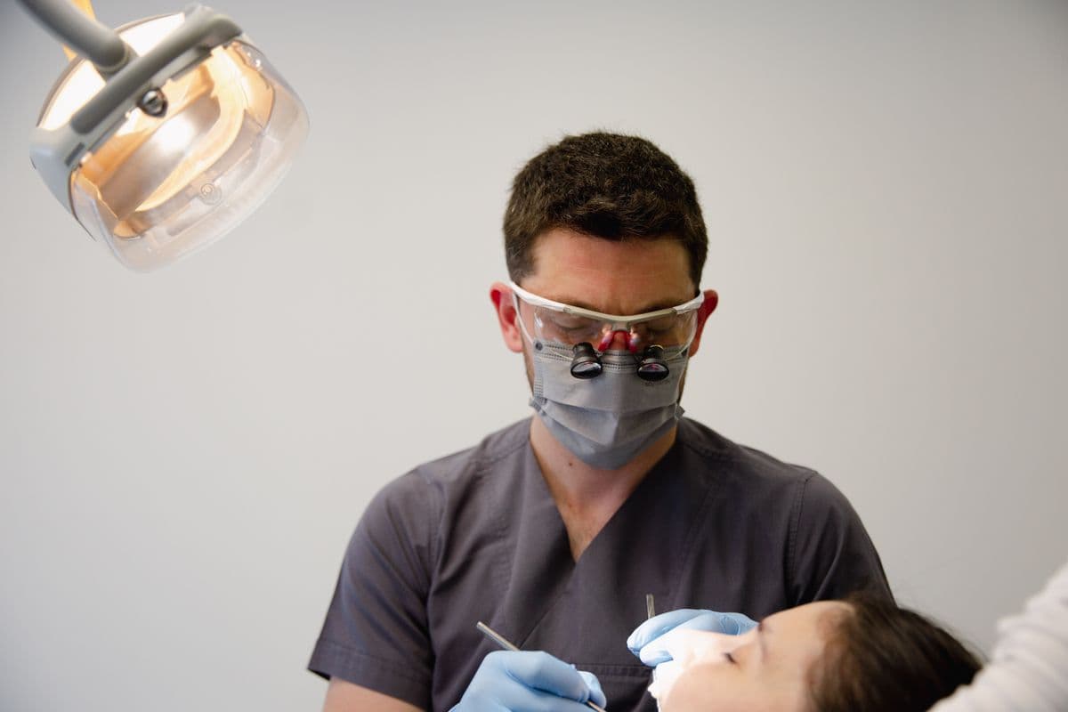 An orthodontist examining a patient's teeth in the treatment chair