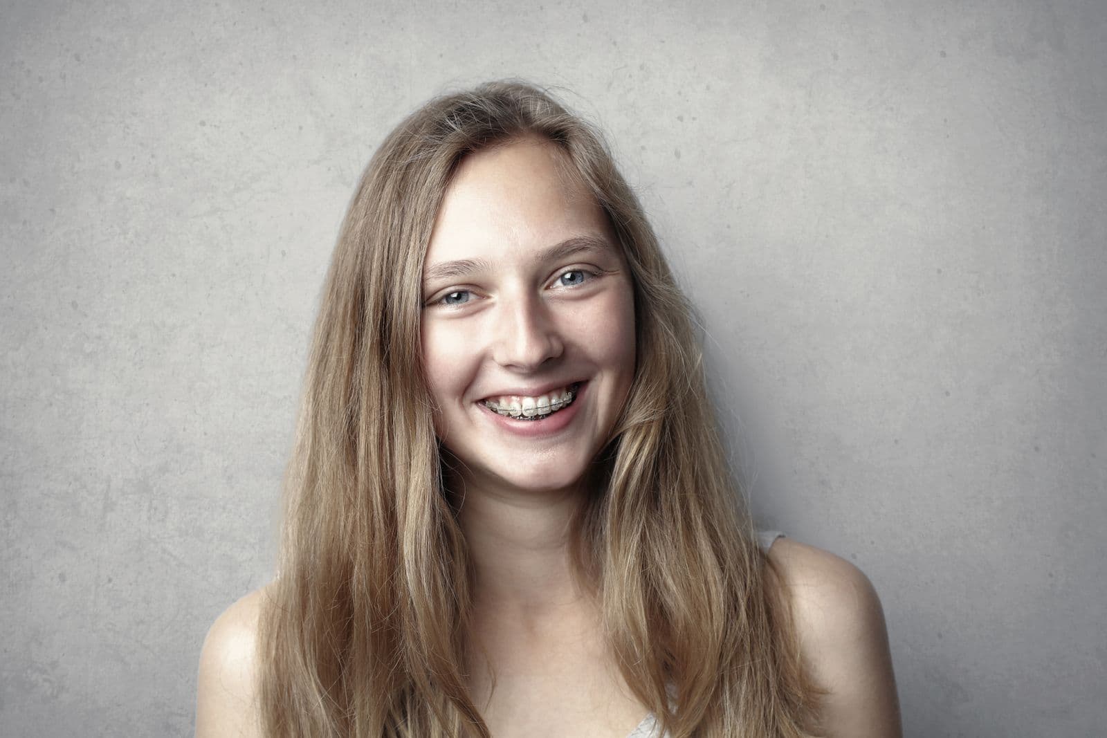 A teenage girl smiling brightly, showing her braces